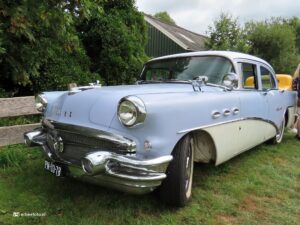Front-left view of a light-blue vintage car with chrome bumper on a grassy area; license plate PM-03-78.